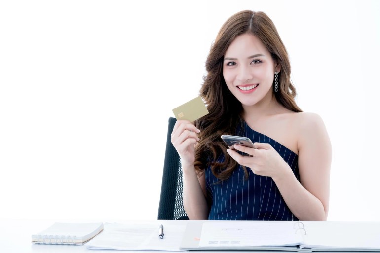 mulher sorrindo com celular e cartao de credito na mao